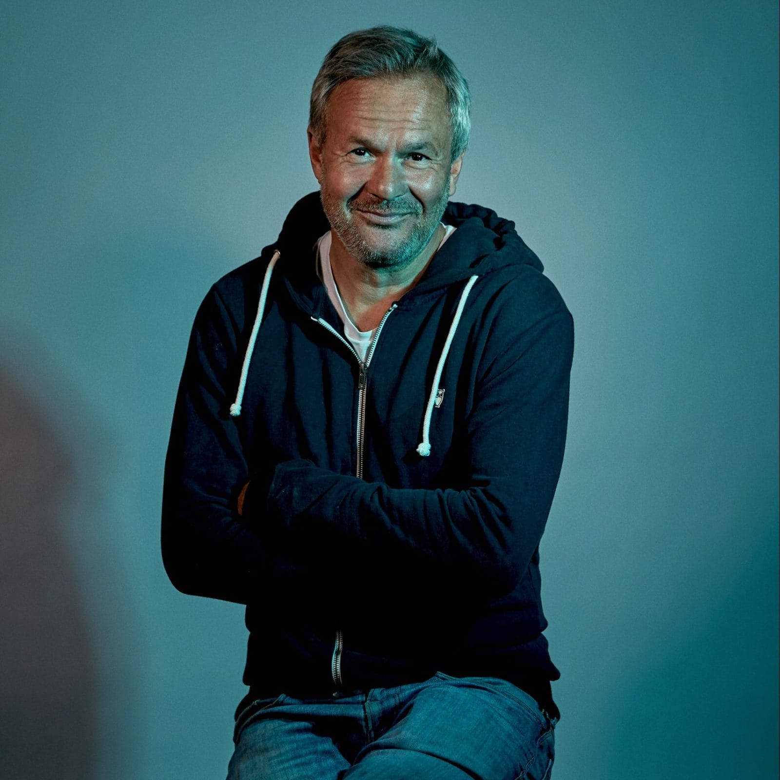 Dan Rachlin siddende med blå baggrund