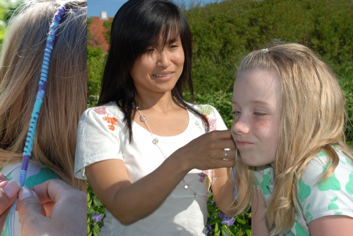 Hiroyo udenfor og laver hårpynt på barn