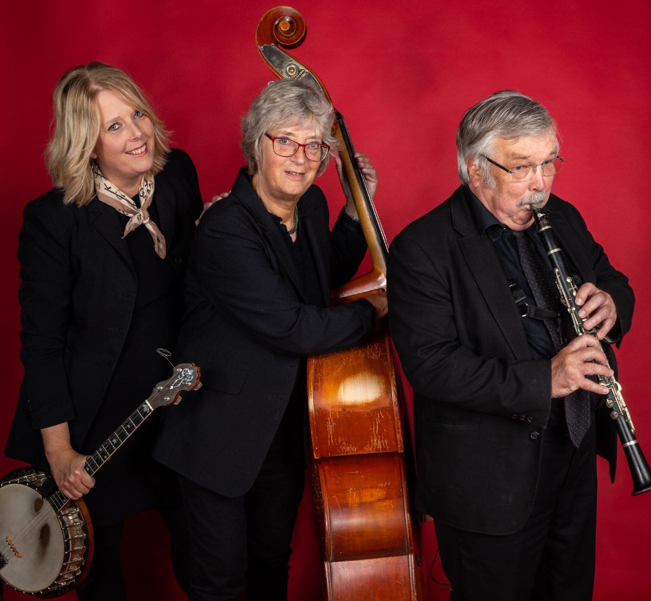 Jensens Jazz Serenaders iført sort tøj ved rød baggrund