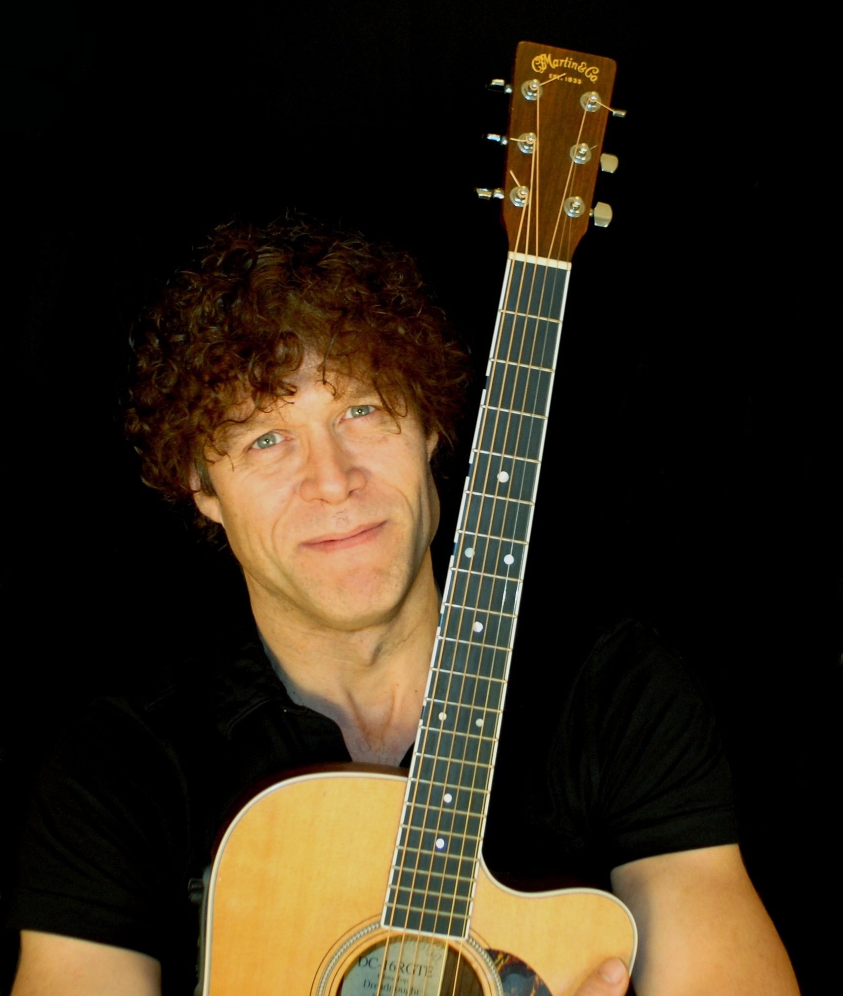 John Pilkington med sin guitar og sort baggrund