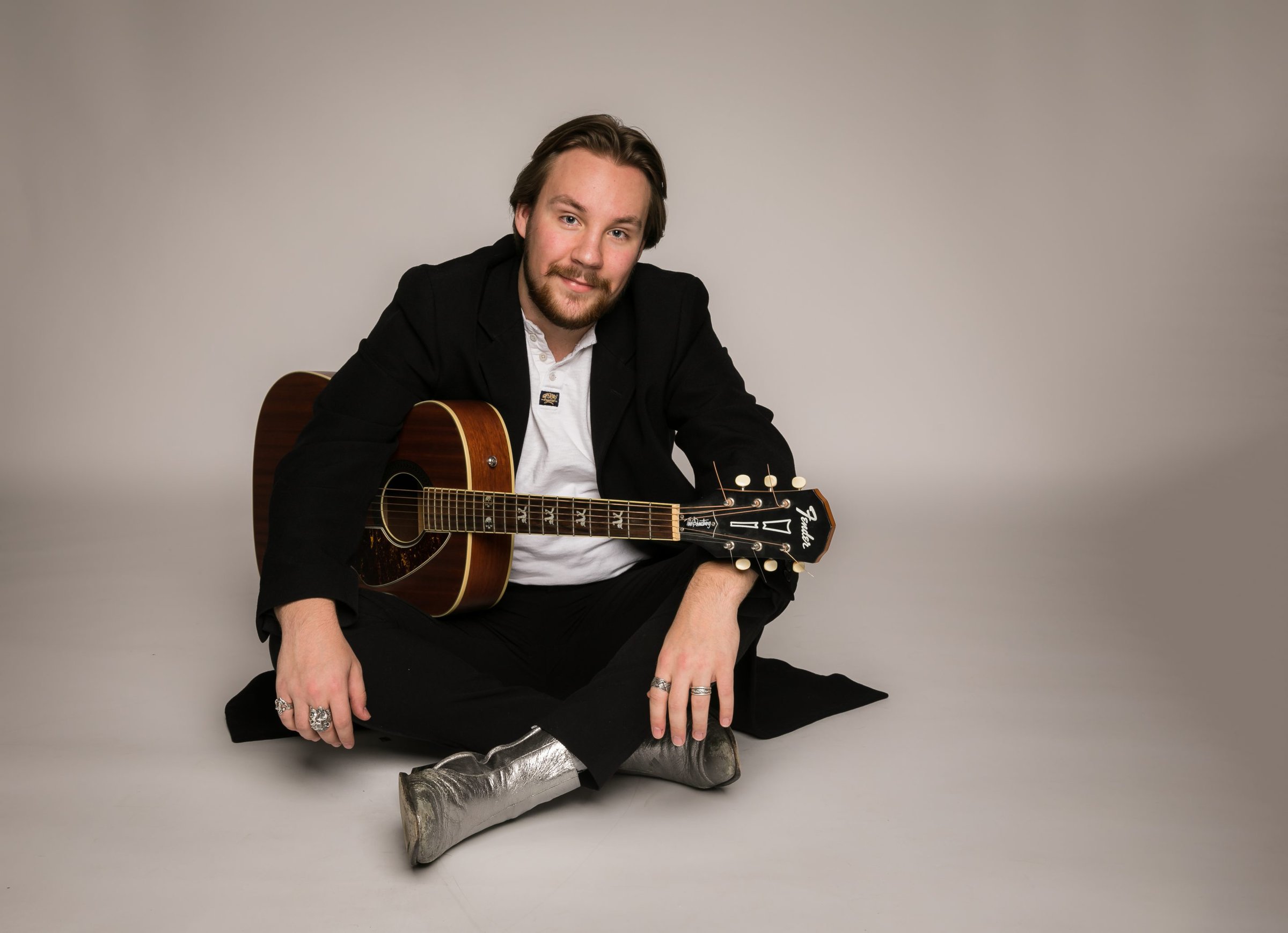 Cai Tonks sidder med gulvet med hvid baggrund