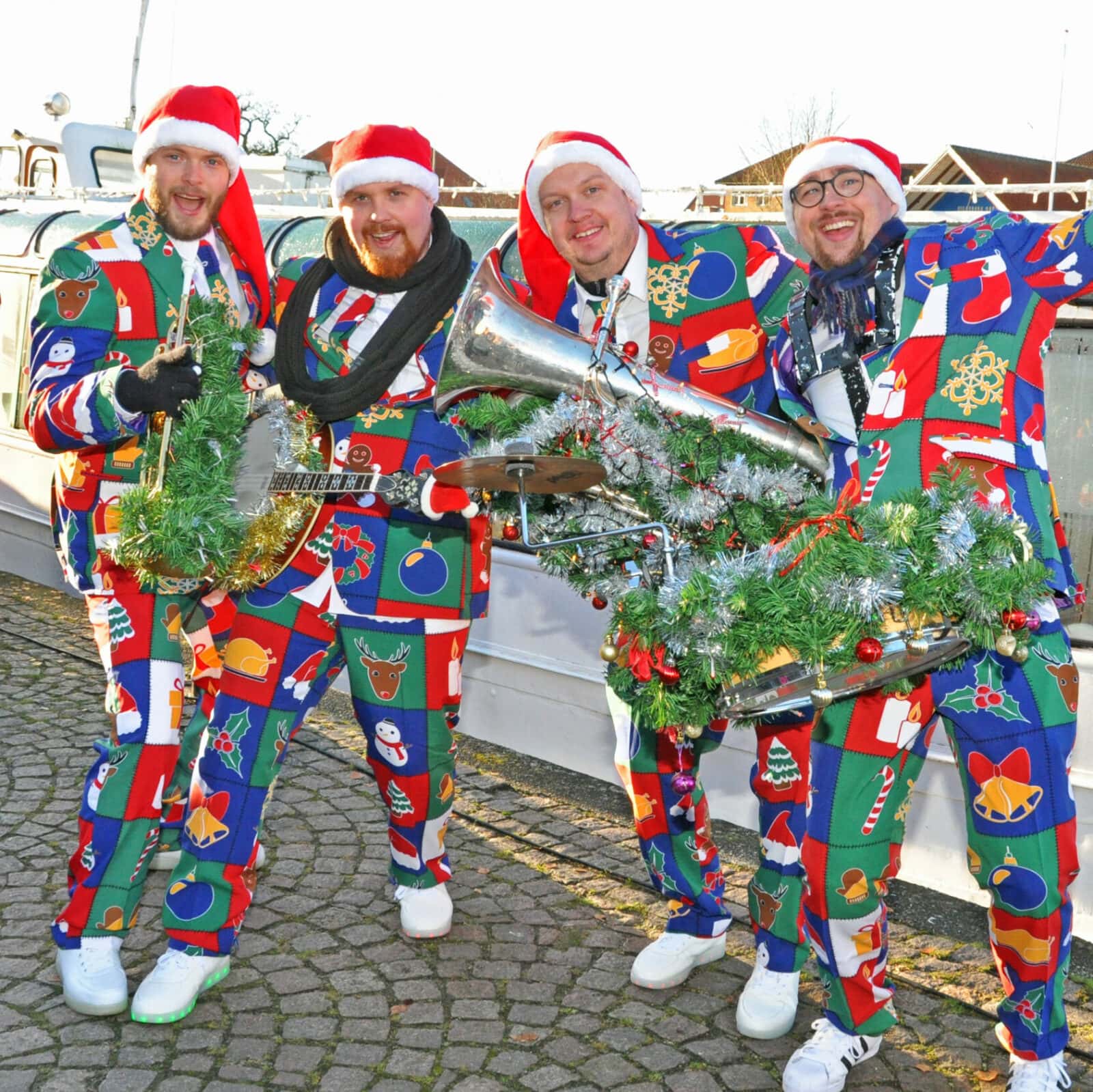 4 mænd i julejakkesæt og instrumenter